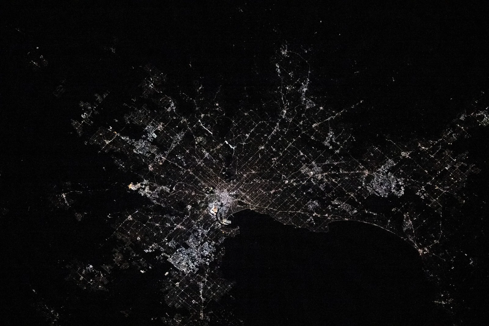 Melbourne’s city lights trace a network of streets around a dark bay, seen from the ISS.